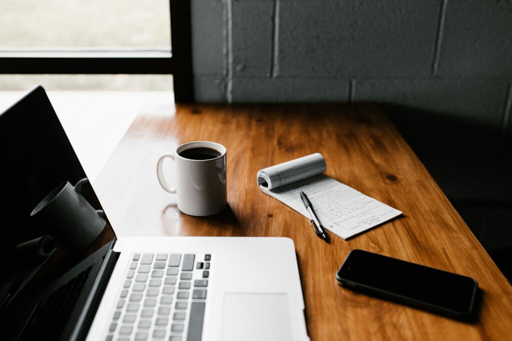 laptop and a note pad with coffee mug illustrates the need for tech startups to blog often.