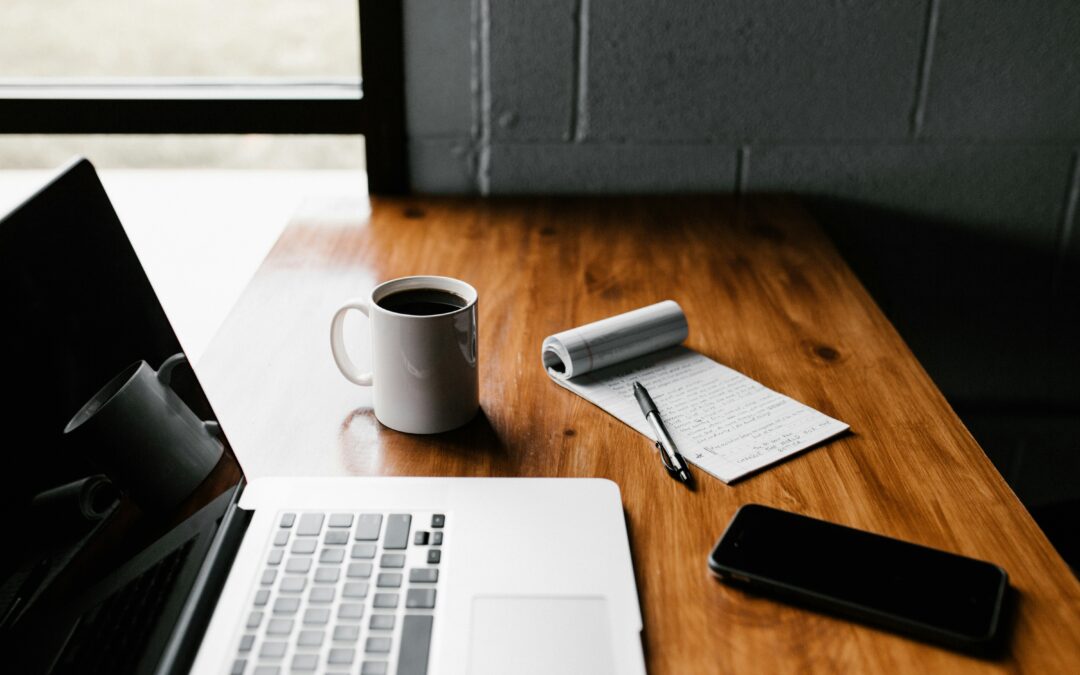 laptop and a note pad with coffee mug illustrates the need for tech startups to blog often.